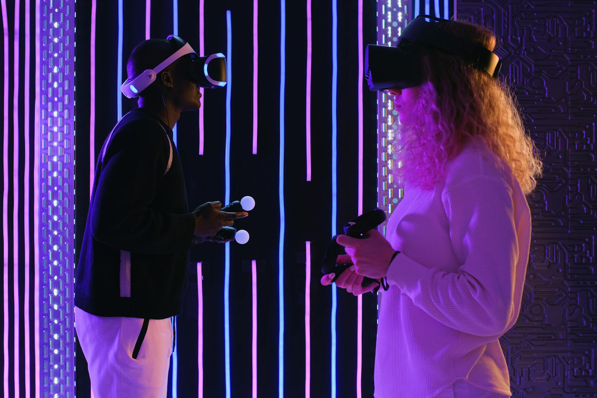 Two adults enjoying virtual reality gaming in a vivid neon-lit room for an immersive experience.